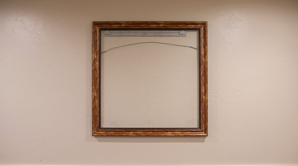 Empty gold frame hanging on a SecurArt mount with tension wire