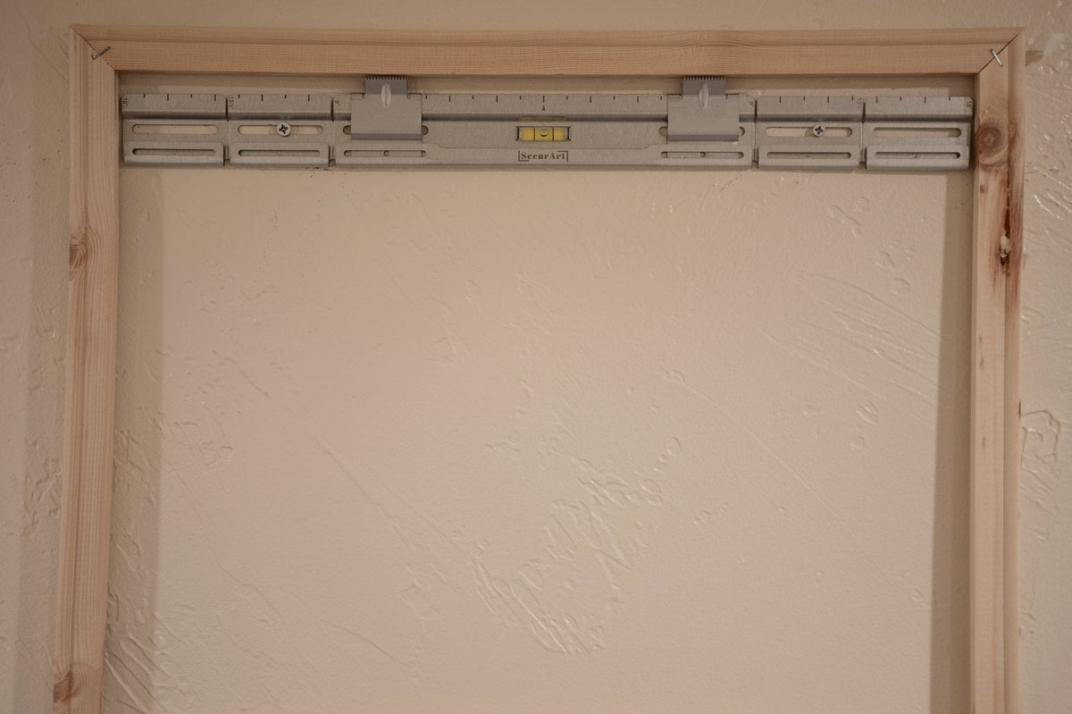 Empty pine stretcher frame on a wall with a SecurArt mount and built-in level across the top