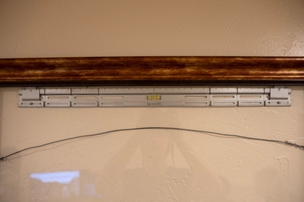 SecurArt mount on a wall with picture wire resting across it