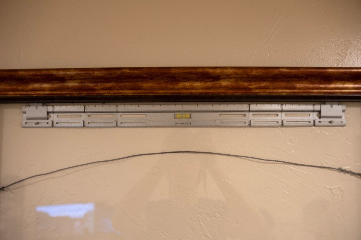 SecurArt mount on a wall with picture wire resting across it