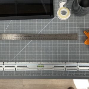 SecurArt wall mount with leveling and measurement features on a cutting mat surrounded by crafting tools.